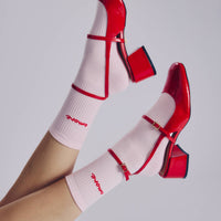 Red high-heeled shoes with white socks featuring red text on a light gray background